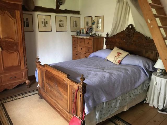 um quarto com uma cama de madeira e uma cómoda em The Manor of Vattetot, historical landmark XII-XVI century em Vattetot-sur-Mer
