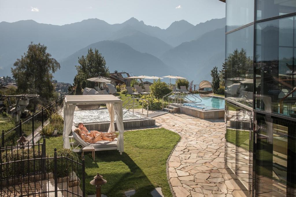 a man laying in a hammock next to a pool at Schlosshotel Fiss in Fiss