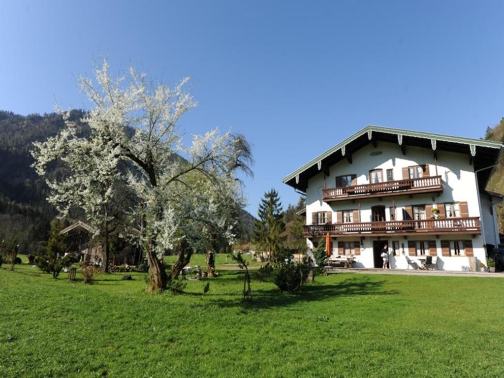 ein großes Gebäude mit einem grünen Feld davor in der Unterkunft Hansenbauernhof in Ruhpolding