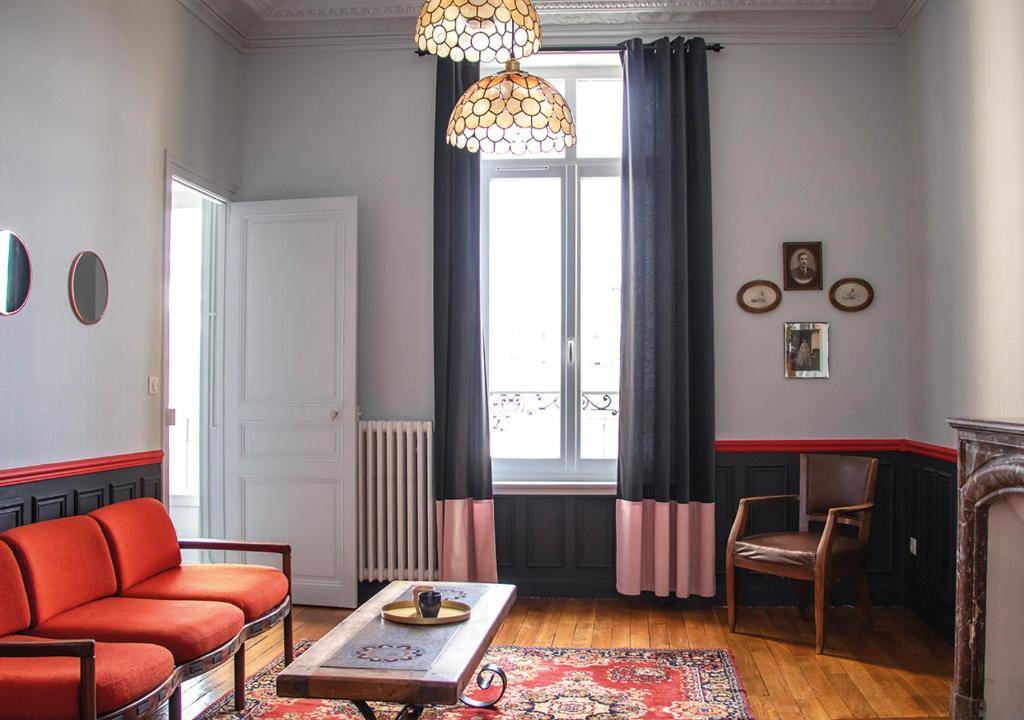 - un salon avec un canapé rouge et une fenêtre dans l'établissement Bel Appartement de Charme - Centre Ville - Quartier du Boulingrin - Gare, à Reims