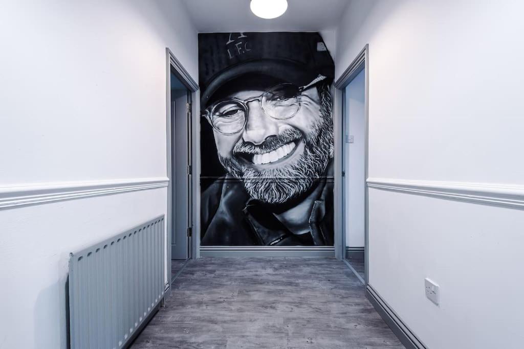 een muurschildering van een man met een bril en een hoed op een muur bij LFC Themed Apartment Anfield in Liverpool