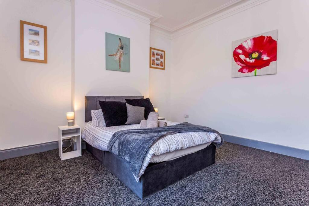 a bedroom with a bed with a red flower on the wall at Guest Homes - Bambro Flat in Sunderland