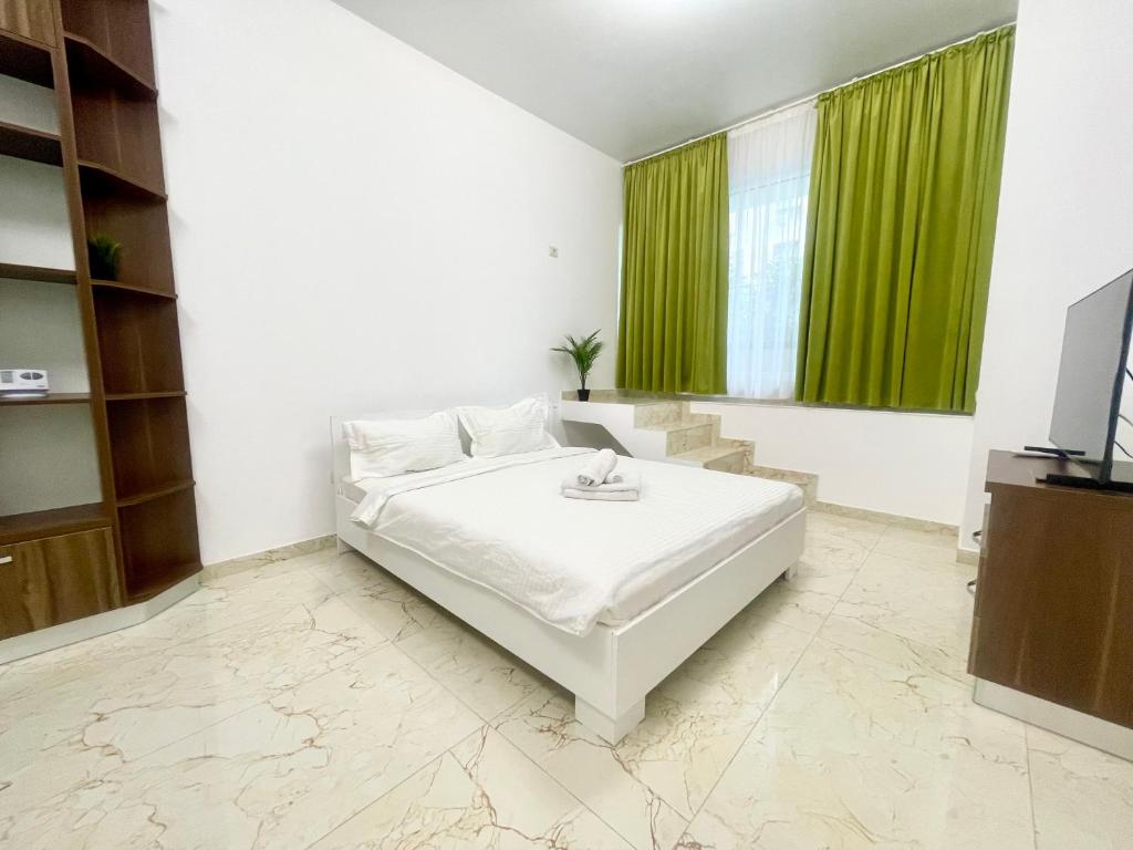 een slaapkamer met een wit bed en groene gordijnen bij Central Adress CD22 in Boekarest