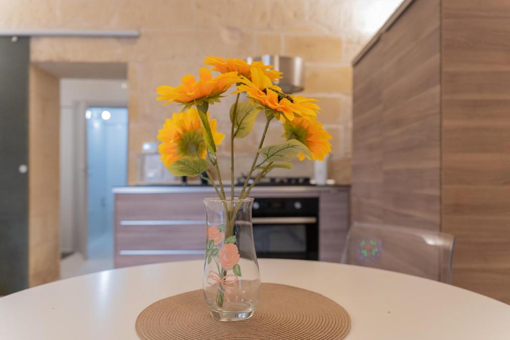 um vaso cheio de flores amarelas sentado numa mesa em DIMORA BAROCCA Apartment Irene em Lecce