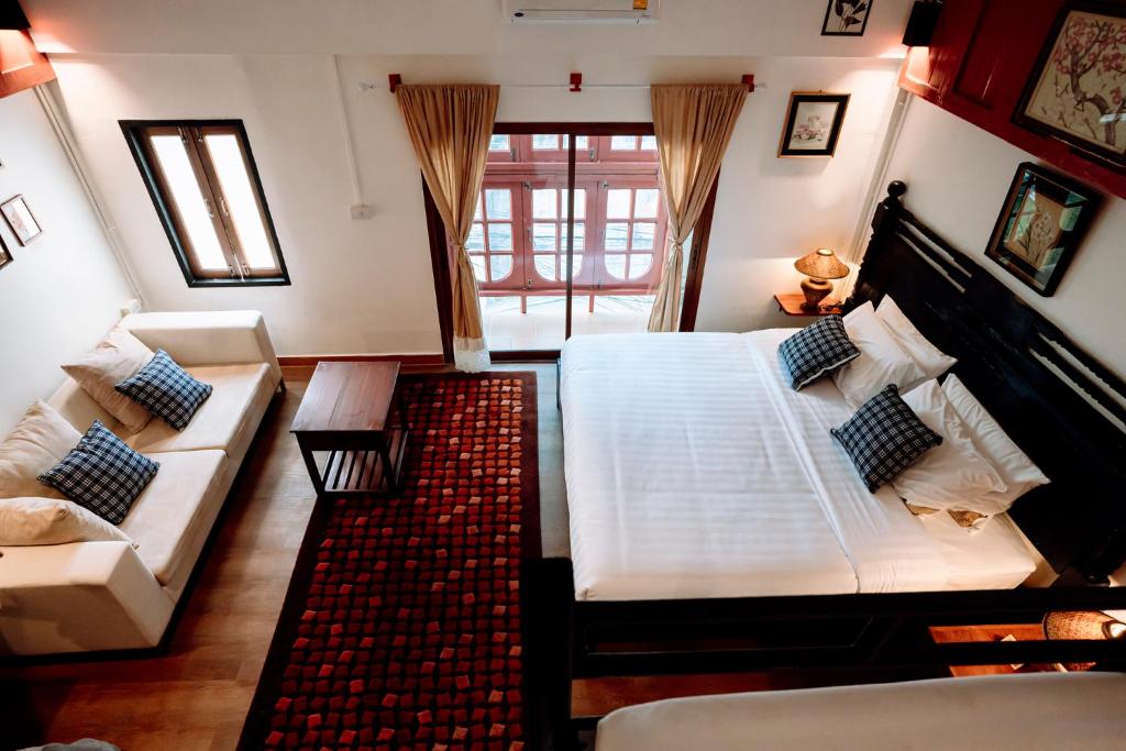 1 dormitorio con 1 cama blanca grande y 1 sofá en Ubon Huan Kaew อุบลเฮือนแก้ว, en Ban Na Khwai