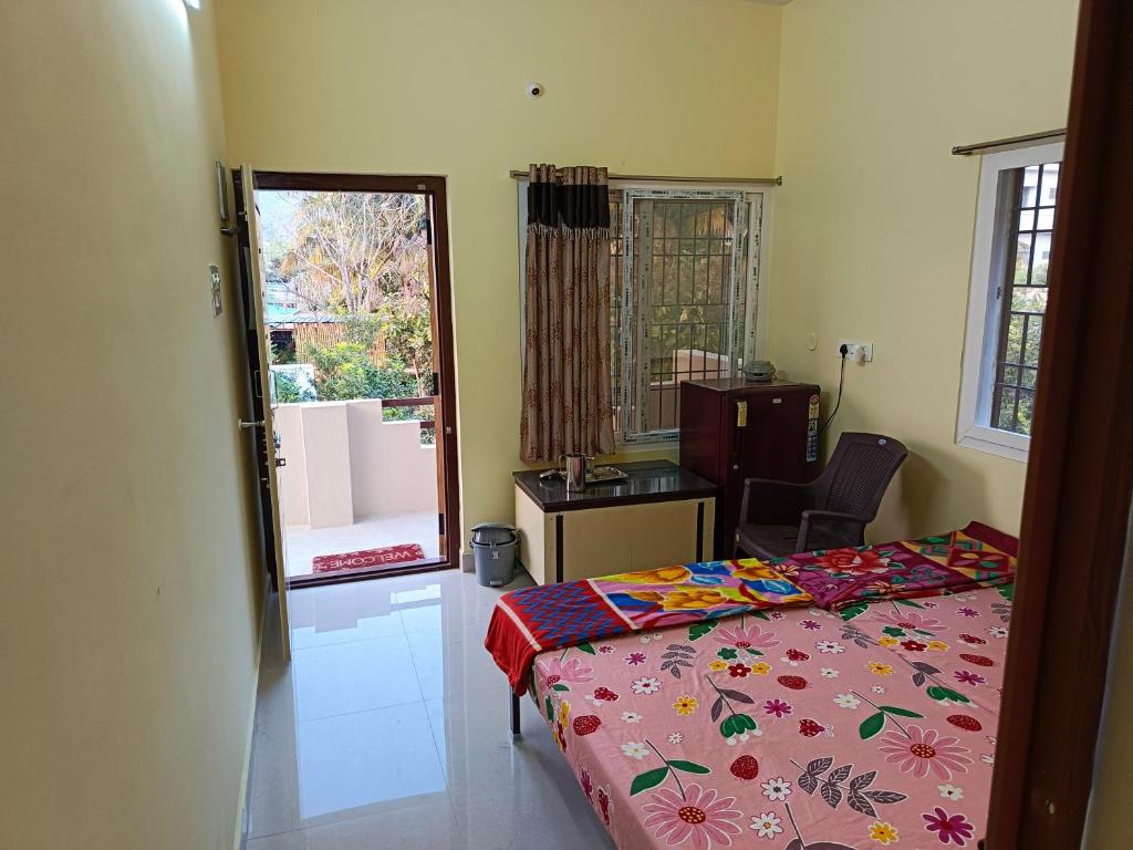a bedroom with a bed and a chair and a window at Abaranji Guest House in Tiruvannāmalai