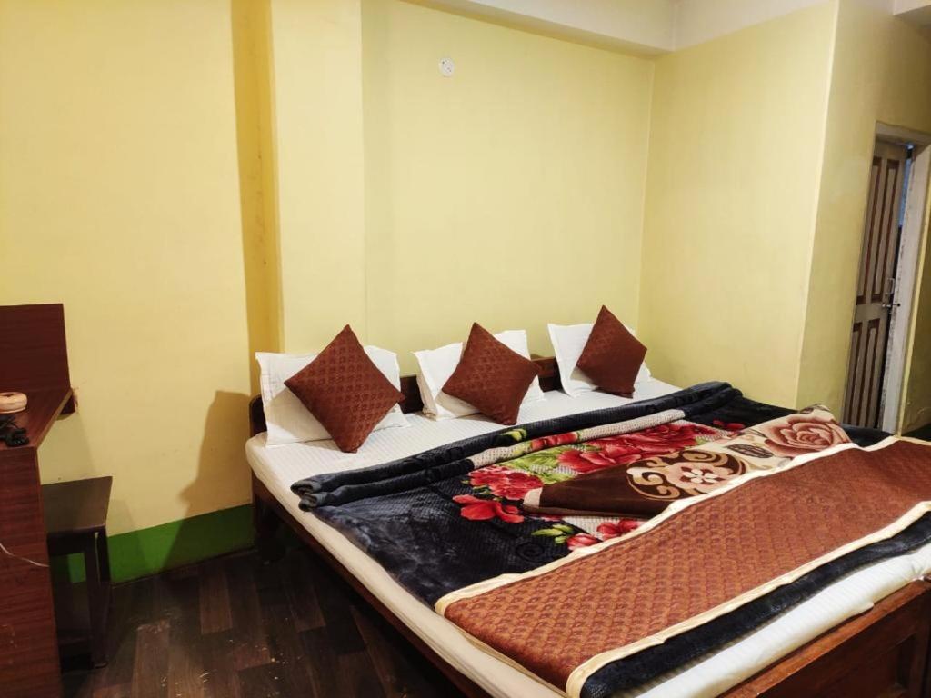 Bett in einem Zimmer mit Kissen darauf in der Unterkunft HOTEL PURNI DARJEELING in Darjeeling