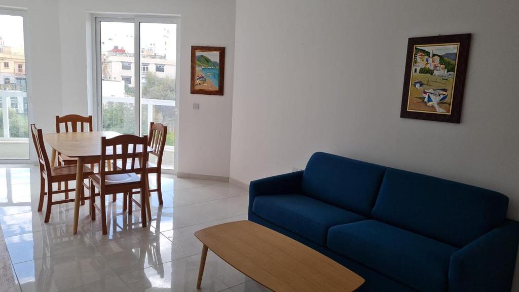 a living room with a blue couch and a table at Msida Central Suites in Msida