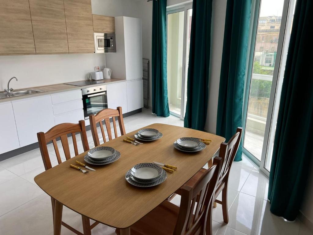 a wooden table in a kitchen with chairs and plates on it at Msida Central Suites in Msida