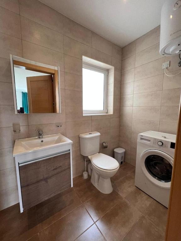 a bathroom with a toilet sink and a washing machine at Msida Central Suites in Msida