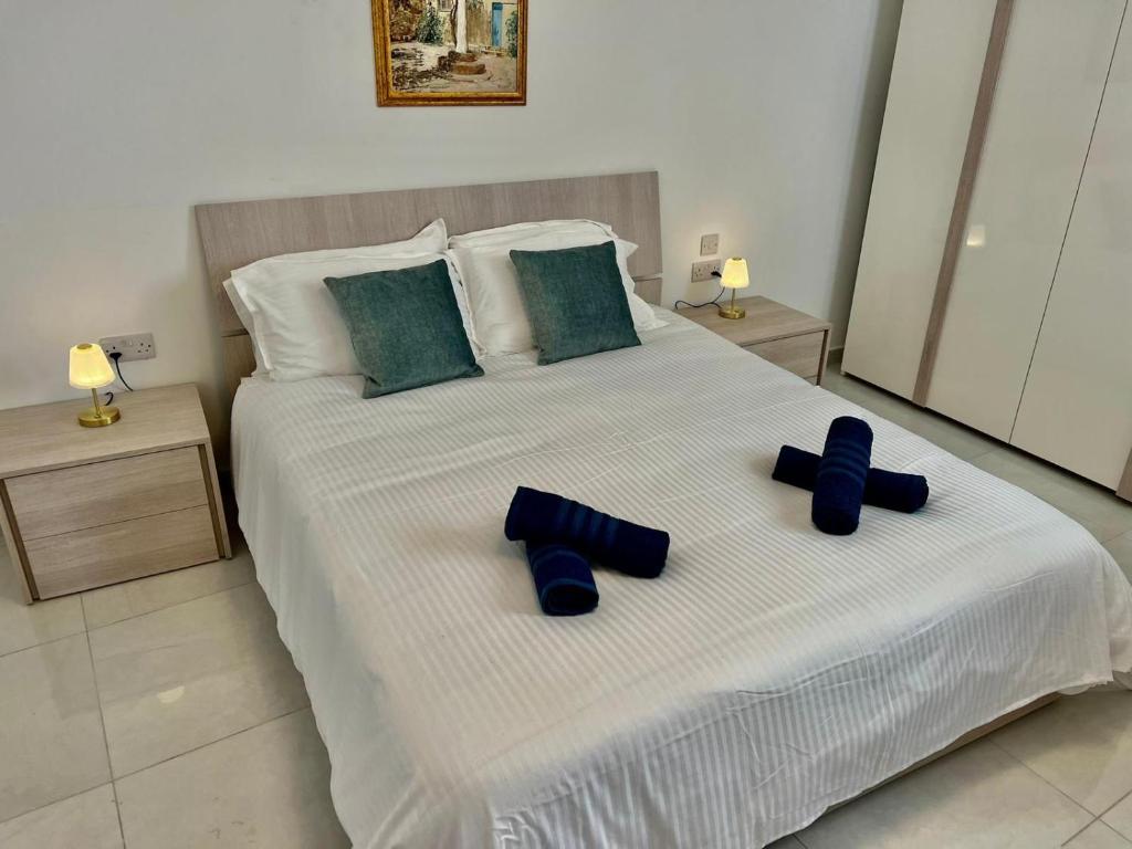 a bedroom with a bed with blue pillows on it at Msida Central Suites in Msida
