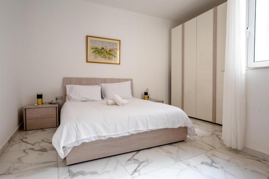 a white bedroom with a large bed with marble floors at Msida Central Suites in Msida