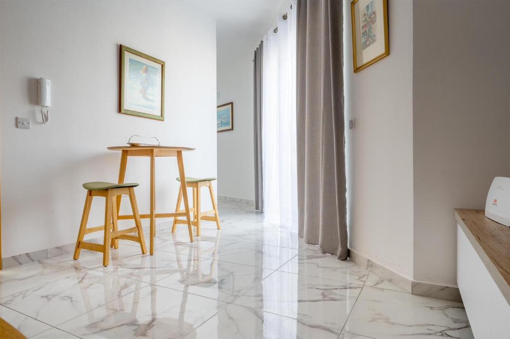 a room with a table and two stools on a marble floor at Msida Central Suites in Msida