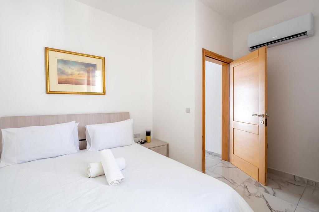 uma cama branca com almofadas brancas num quarto em Msida Central Suites em Msida