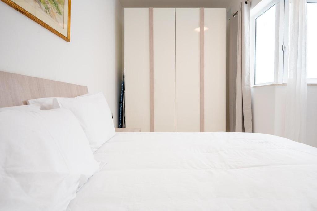 a white bed in a bedroom with a window at Msida Central Suites in Msida