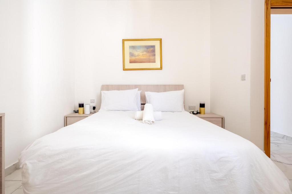 a white bed with white sheets and pillows at Msida Central Suites in Msida