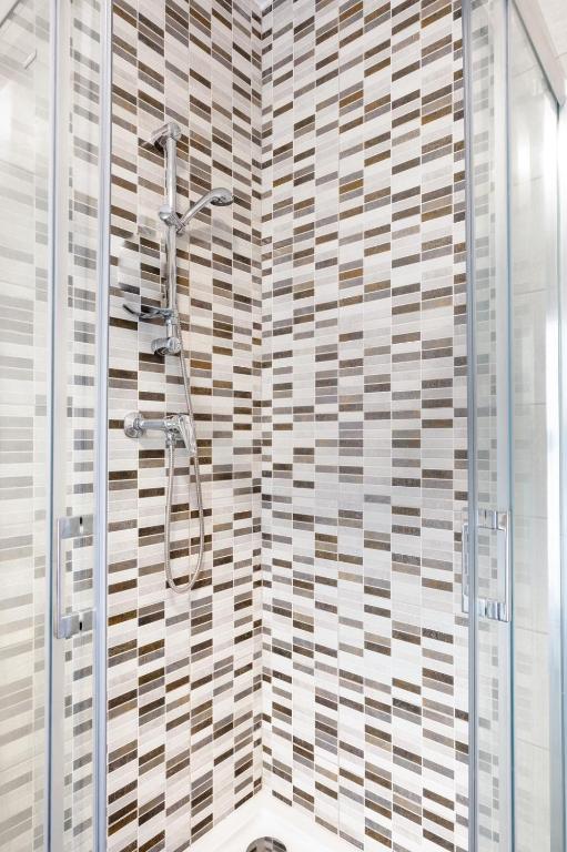 a shower in a bathroom with a tile wall at Msida Central Suites in Msida