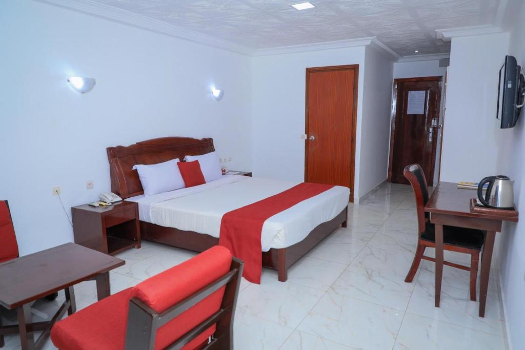 a bedroom with a bed and a table and a chair at HÔTEL MARIADOR PARK in Conakry