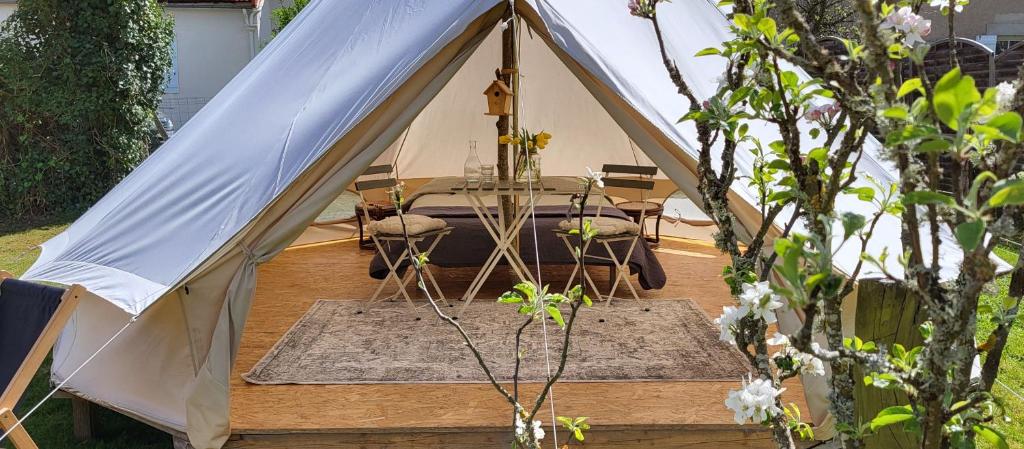 a tent with a table and chairs in a yard at Petit a Petit - gypsy wagons and Bell tents in the Bourgogne in Saisy