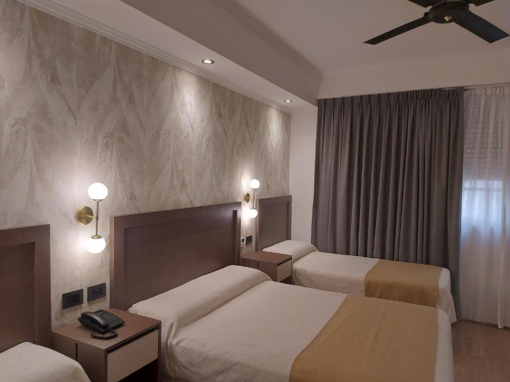 a hotel room with two beds and a ceiling fan at Hotel Internacional in Buenos Aires