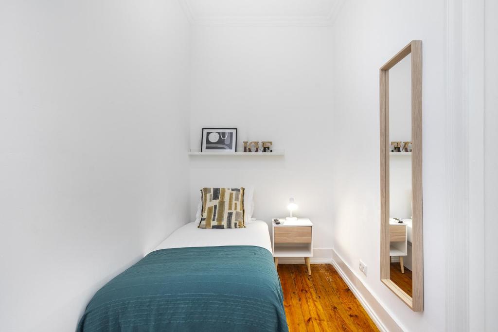 a white bedroom with a bed and a mirror at Modern Nomad Hub Stylish Spaces for Remote Living in Lisbon