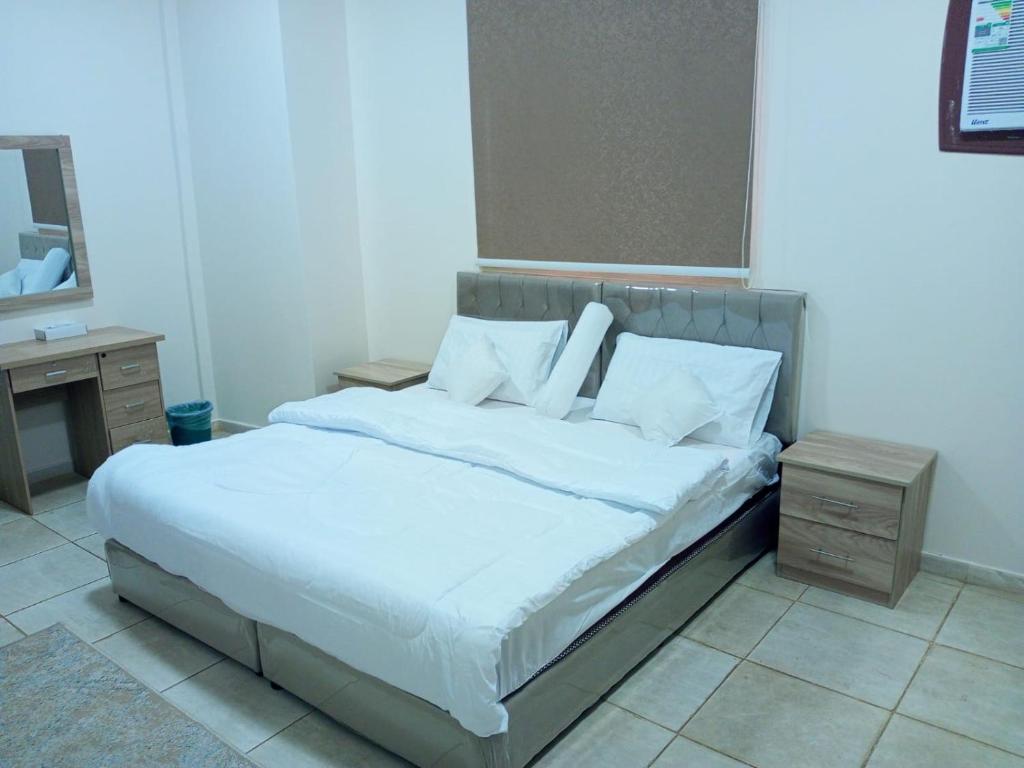 uma cama com lençóis brancos e almofadas num quarto em شقق الفتح الخاصة Al-Fateh Private Apartments em Medina