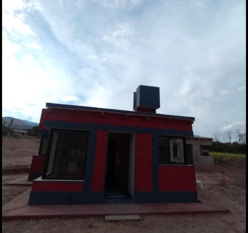una casita roja y azul con una chimenea en la parte superior en Cabañas Riviera, en Huacalera