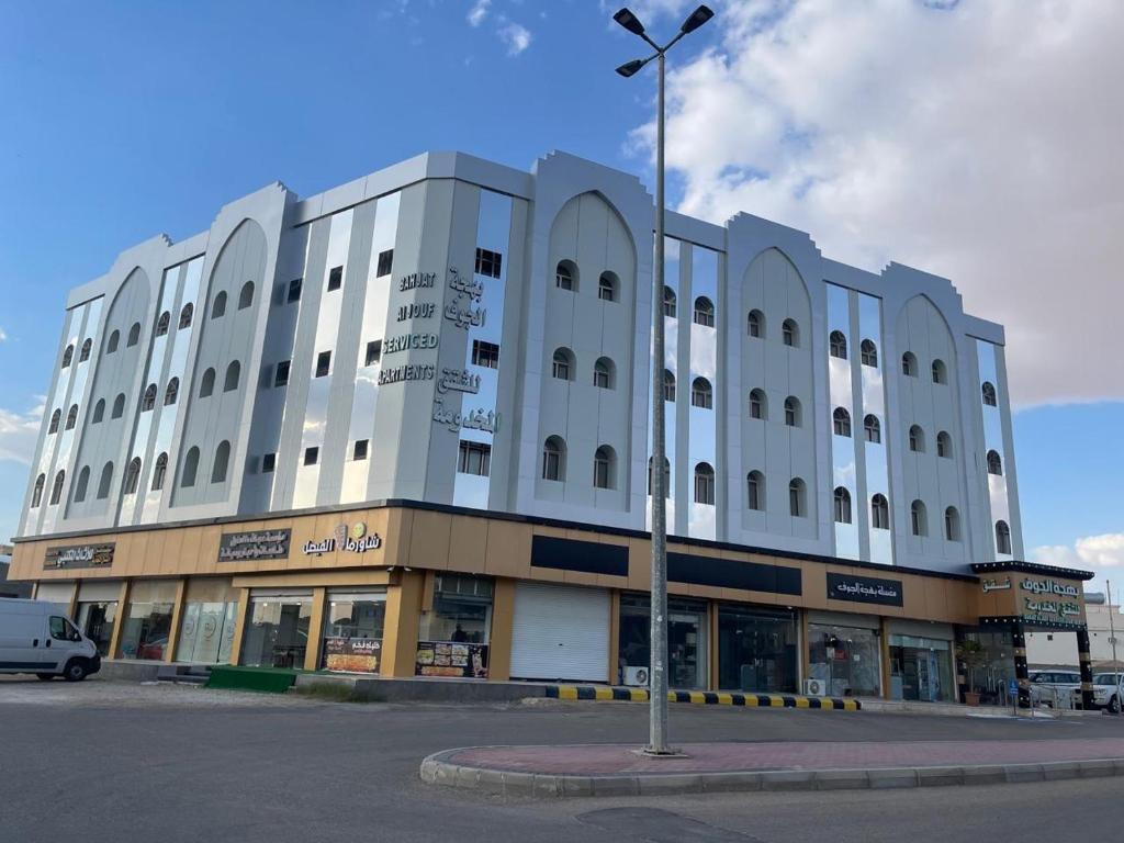 un grande edificio bianco con un lampione davanti di Bahget Eljouf Furnished Apartment a Aţ Ţuwayr
