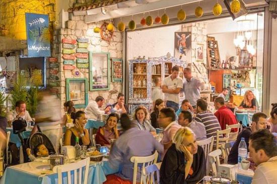 un grupo de personas sentadas en mesas en un restaurante en Alsancak Konak seaside 50 mt walk Double room, en Konak