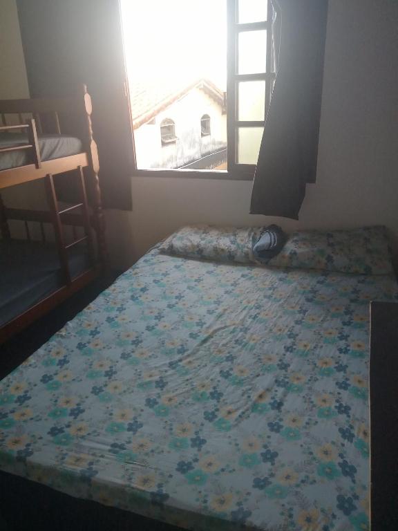 a bedroom with a bed and a window with a bedspread at Pousada verde mar in Cabo Frio