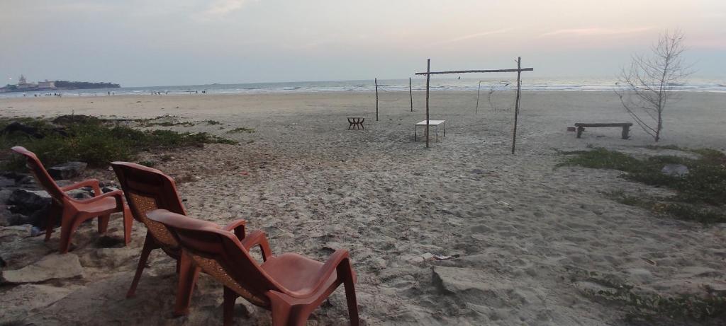 two chairs and a bench on a beach at Nestle Beachfront Murudeshwar in Māvalli