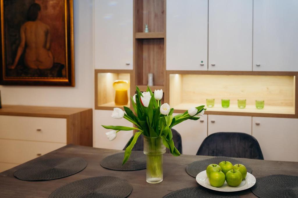 a dining room table with a vase of flowers and apples at Krum khan Top Centre Apartment in Sofia