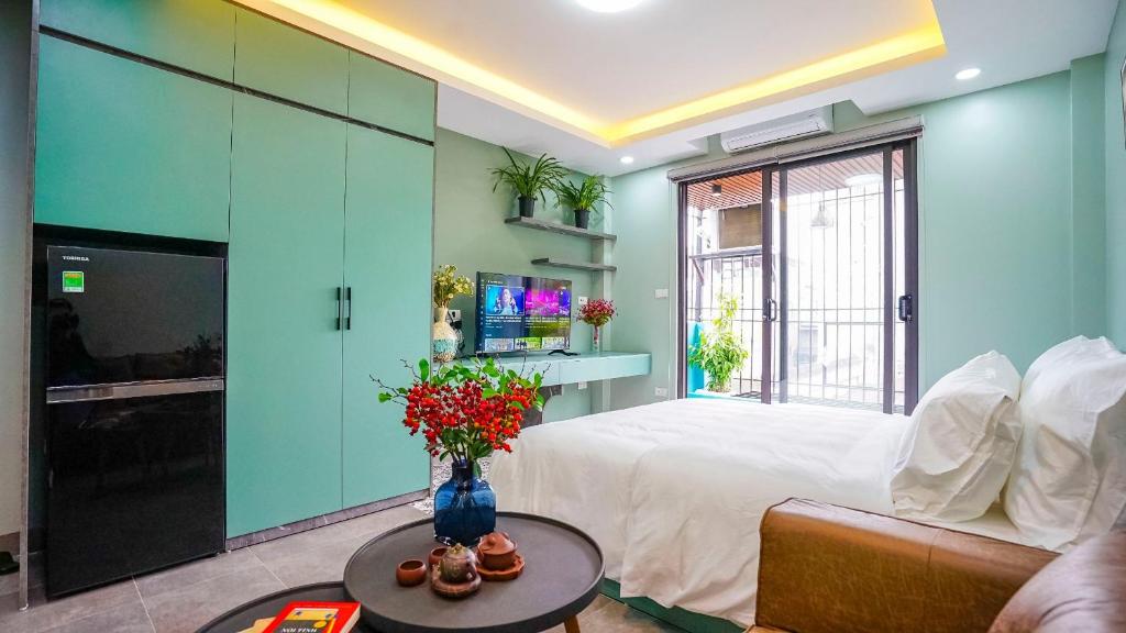 Hanoi Ben's Apartment and Hotel في هانوي: غرفة بسرير وطاولة مع ورد