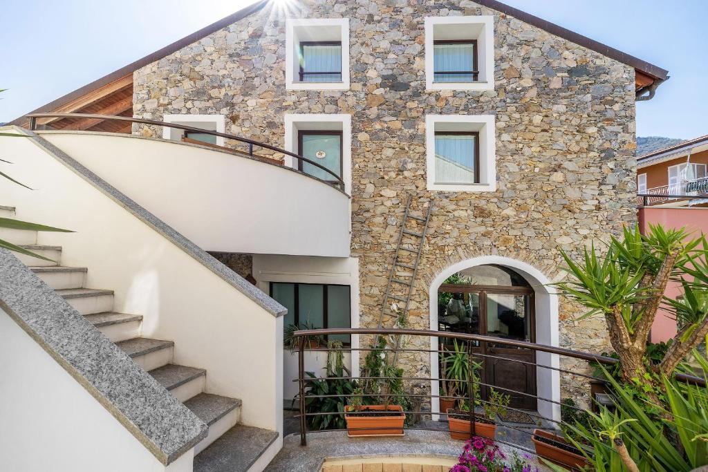 a stone house with a staircase in front of it at Melograno Agriturismo La Ferla in Toirano