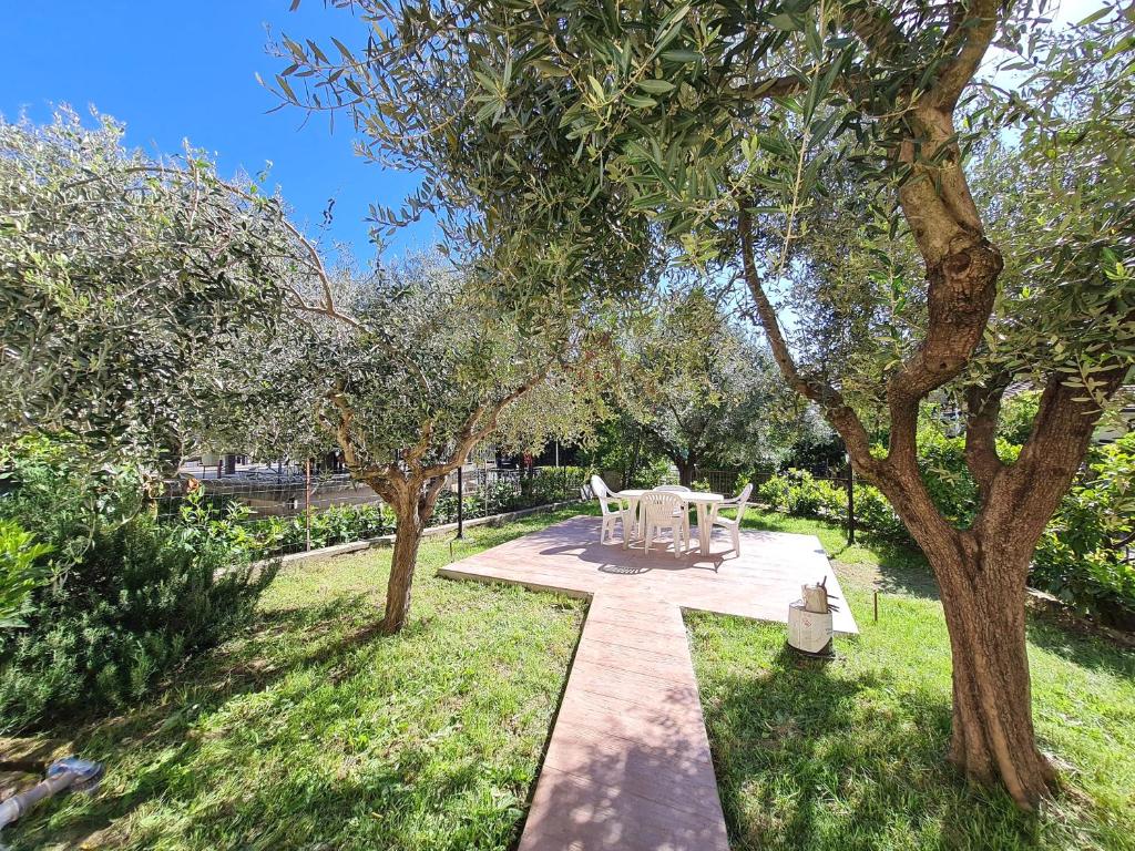 un jardín con mesa, sillas y árboles en Appartamento Pederzoli, en Peschiera del Garda