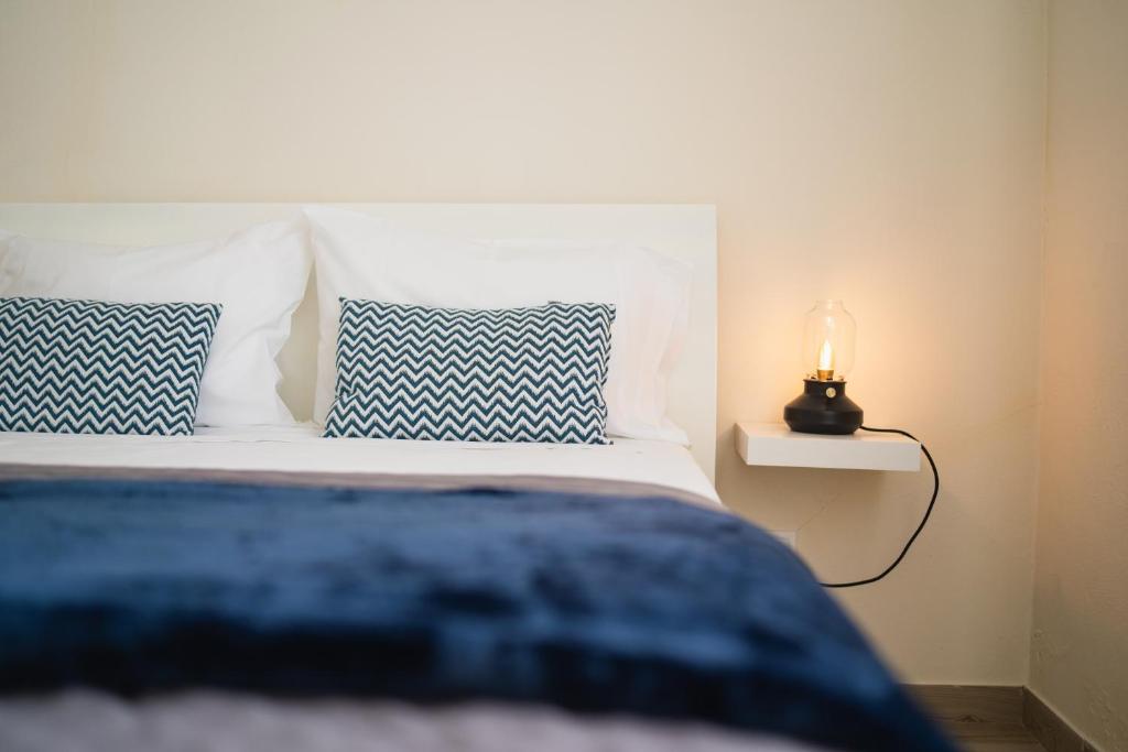 Una cama con almohadas azules y blancas y una lámpara. en Casas do Navalhão en São Roque do Pico