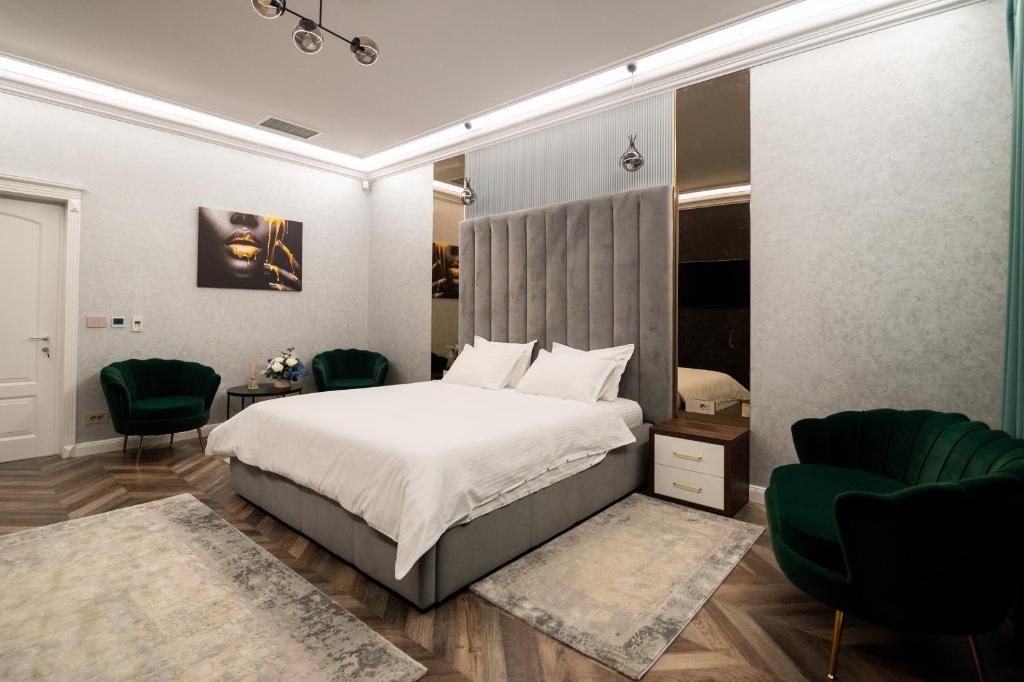 1 dormitorio con 1 cama y 2 sillas verdes en The Penthouse, en Vaslui