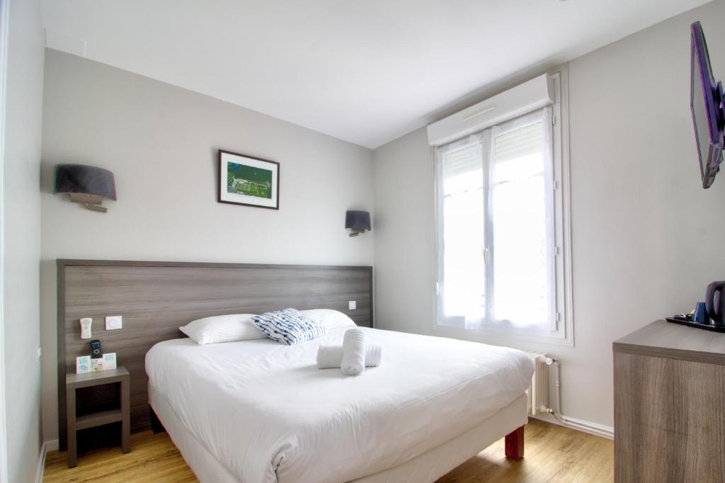 a bedroom with a white bed and a window at Logis Hôtel Des Châteaux De La Loire in Tours