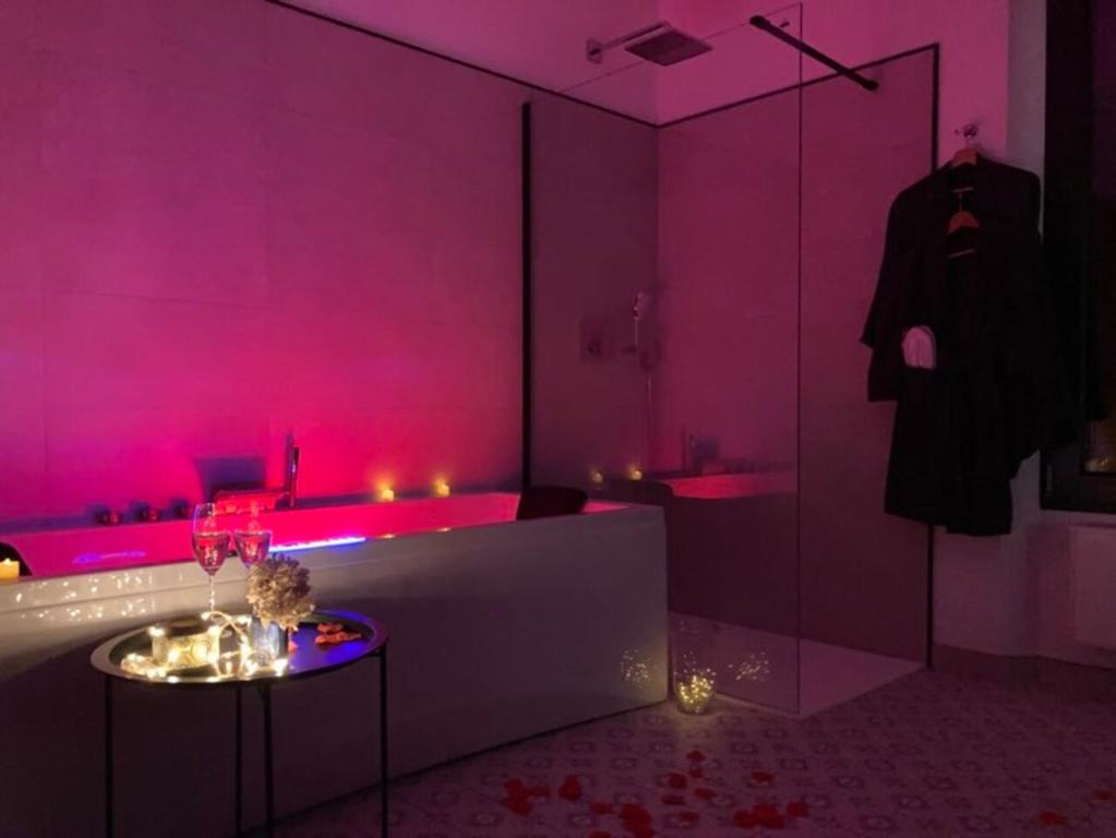 Cette chambre rose comprend une baignoire et une table. dans l'établissement Domaine du lion rouge, à Coucy-le-Château-Auffrique