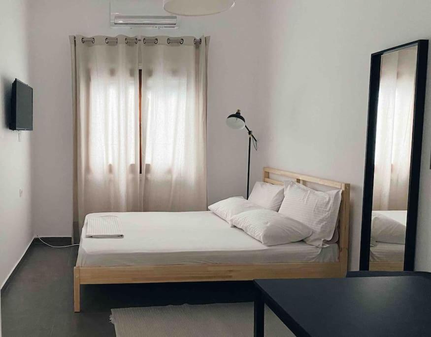 a bed with white sheets and a mirror in a room at City Center Studio Apartment in Heraklio