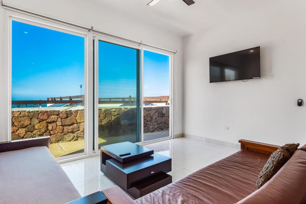 a living room with a couch and large windows at Casa Marfil 26 - Playa Arcangel in Rosarito