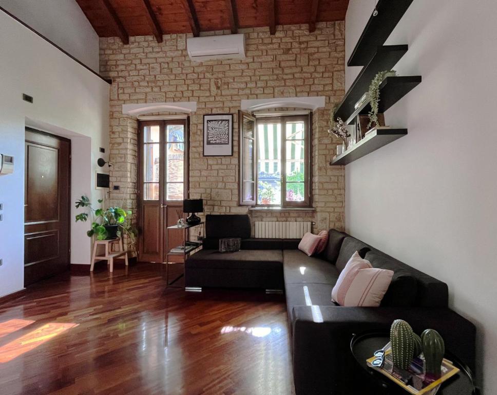 Civico 24 في كريمونا: غرفة معيشة مع أريكة سوداء وجدار من الطوب