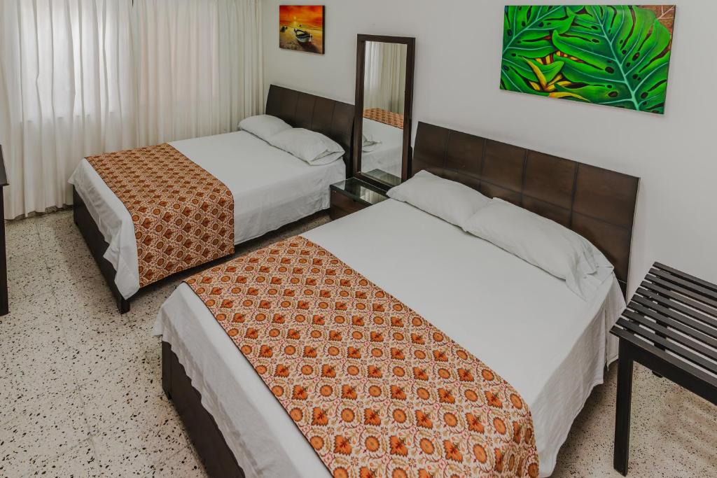 a hotel room with two beds and a mirror at Casa Hotel Miriam in Montería