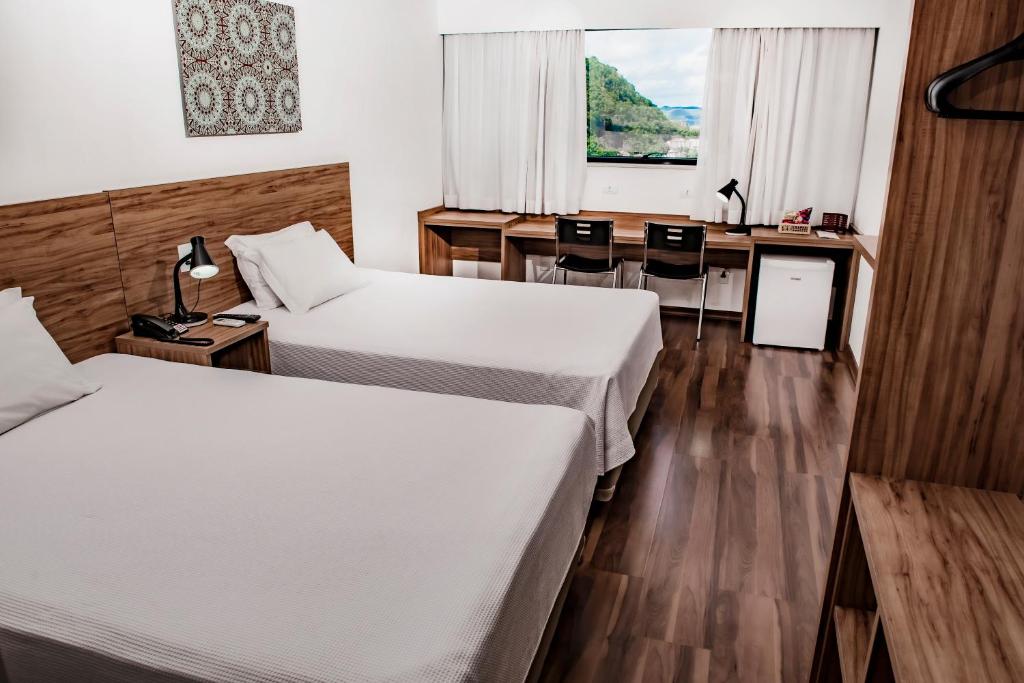 een hotelkamer met 2 bedden en een bureau bij Trade Hotel in Juiz de Fora