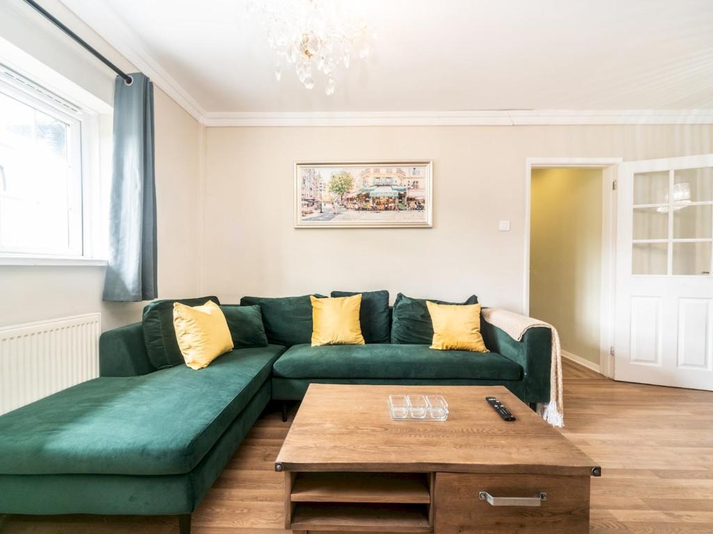 a living room with a green couch and a coffee table at Lovely cosy gem with free parking Pass the Keys in Surbiton