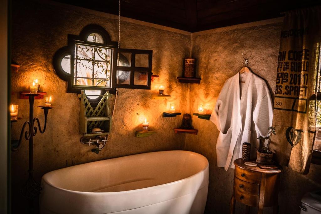 a bathroom with a tub and a robe and lights at Baraka Antigua in Antigua Guatemala