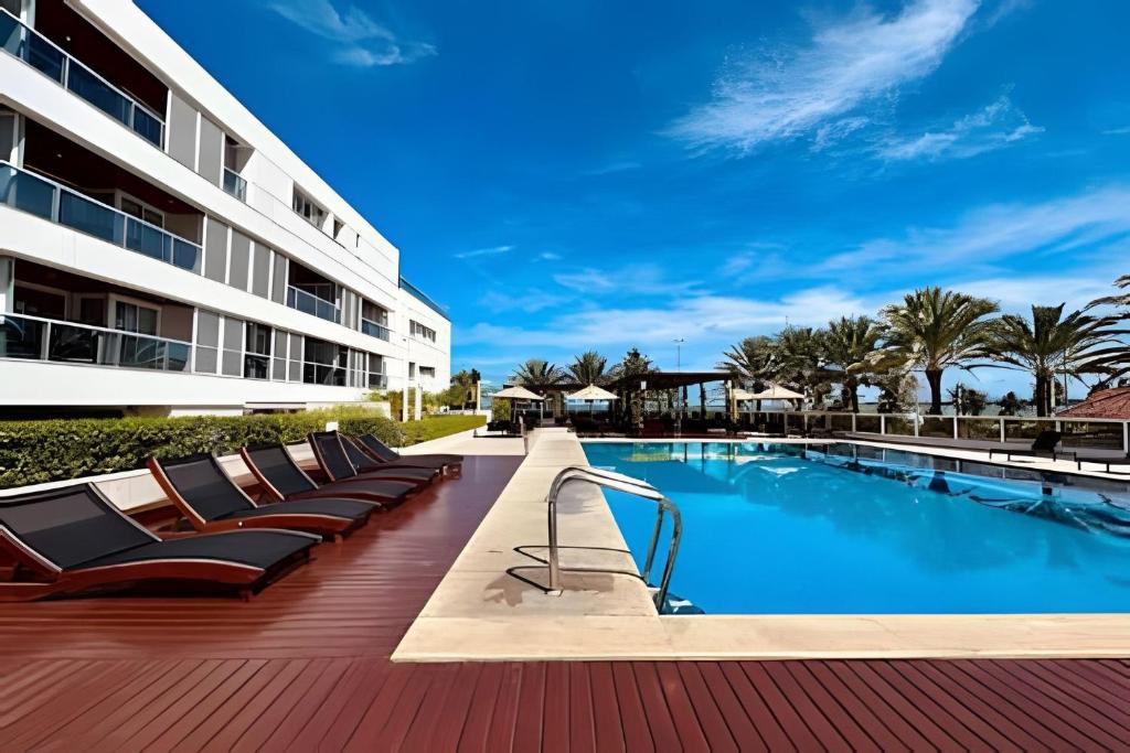 a resort swimming pool with lounge chairs and a building at Luxo à beira-mar no Solar Tambaú in João Pessoa