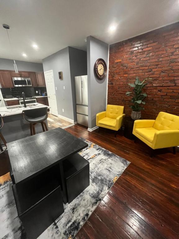 a living room with yellow furniture and a brick wall at Feel at home when you’re away in Philadelphia