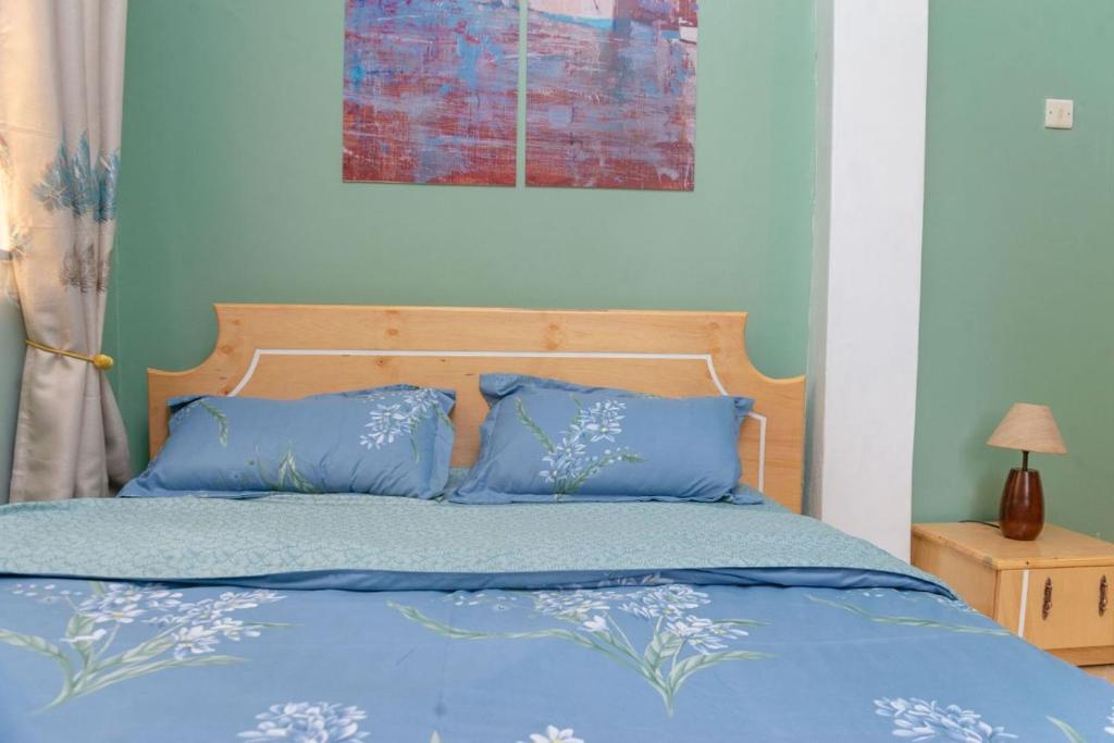 een slaapkamer met een blauw bed met blauwe kussens bij COZY COOL ,WIFI 6 MINS WALK TO ACACIA MALL in Kampala