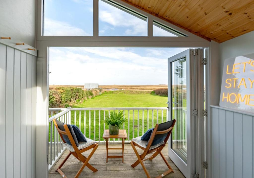 a porch with two chairs and a balcony with a view at Dolphin Cottage - Brancaster Staithe in Brancaster